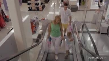 年轻<strong>的</strong>父母带着购物袋和小儿子手里拿着柔软<strong>的玩具熊</strong>乘电梯进来
